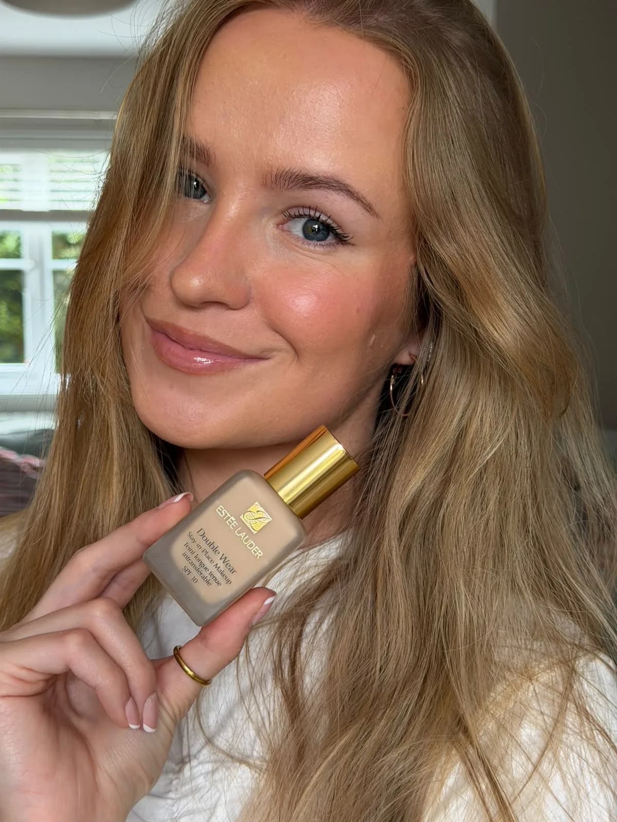 Abbie McDonnell holding a bottle of Estee Lauder Double Wear foundation while wearing it