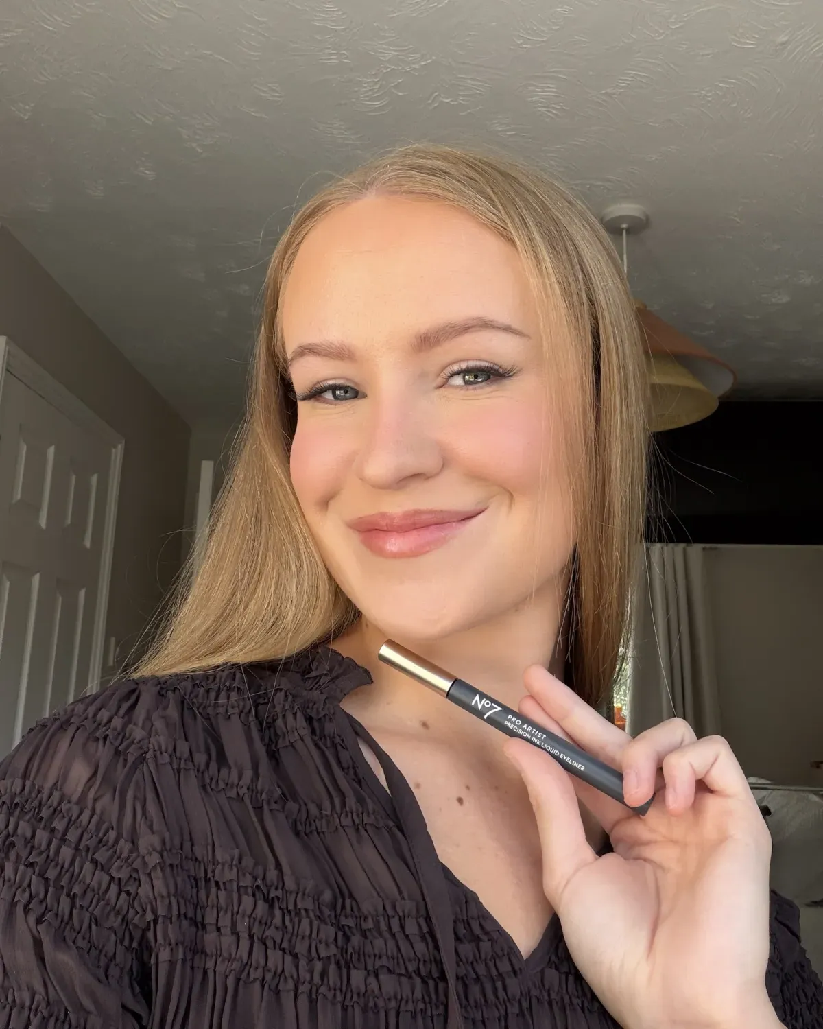 Me holding the No7 Pro Artist Precision Ink Liquid Eyeliner, wearing it in Noisette Brown