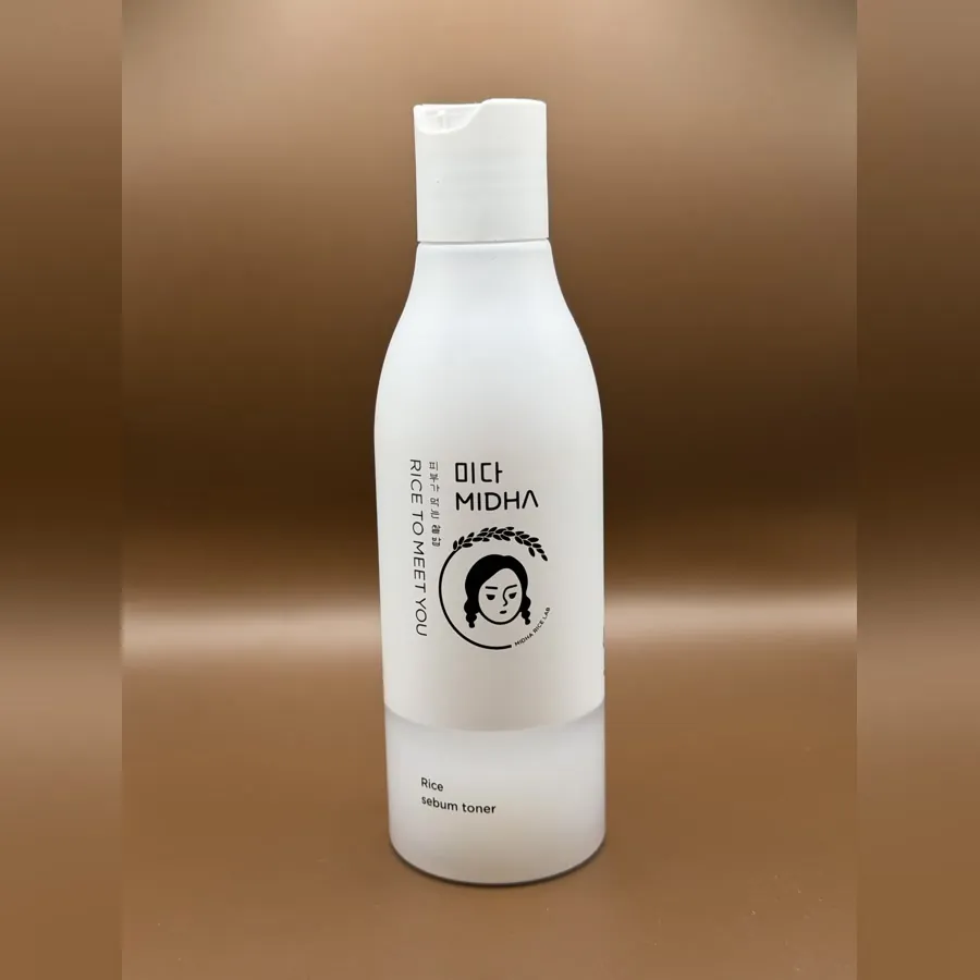 MIDHA Rice To Meet You rice sebum toner in a white bottle with an illustrated face